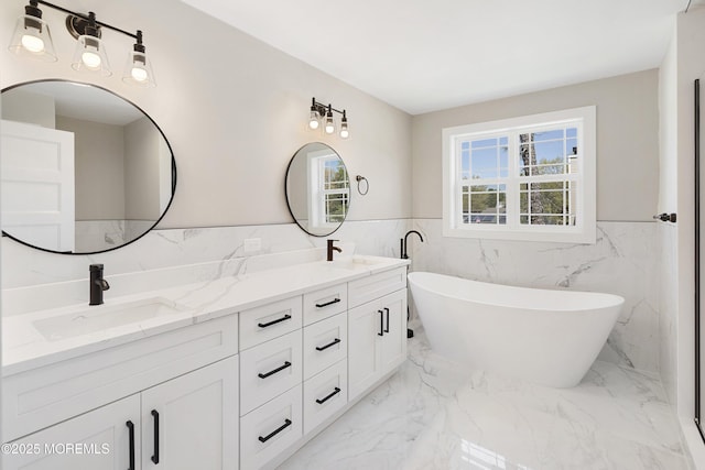 bathroom with double vanity, tile walls, a wainscoted wall, a soaking tub, and a sink