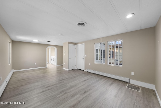 unfurnished living room featuring arched walkways, visible vents, wood finished floors, and a baseboard radiator