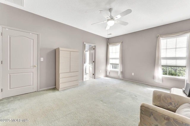 living area with ceiling fan, carpet, and a wealth of natural light