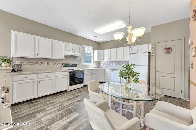 kitchen with decorative backsplash, white appliances, under cabinet range hood, white cabinets, and a chandelier