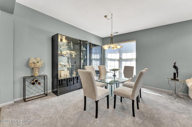 carpeted dining area featuring baseboards, an inviting chandelier, and visible vents