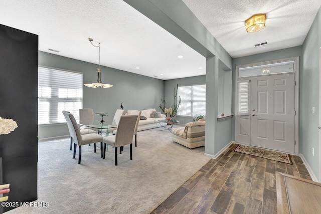 carpeted entryway with baseboards, a textured ceiling, wood finished floors, and visible vents