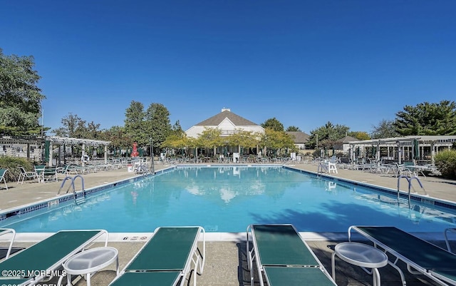 community pool with a patio area and a pergola