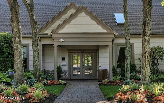 entrance to property with french doors, a shingled roof, and a chimney