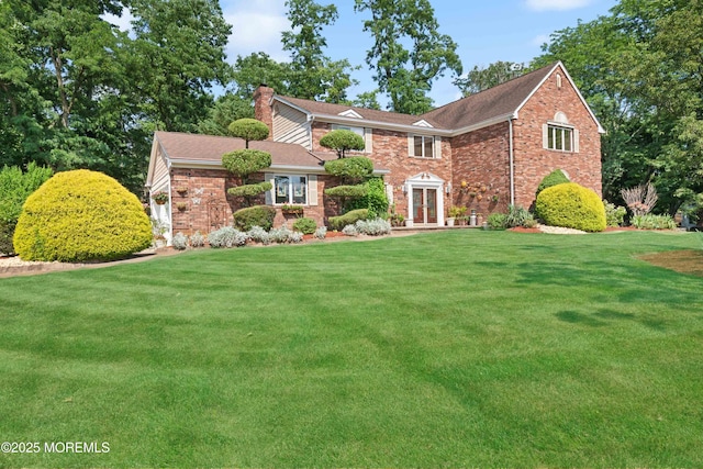 view of front facade with french doors, brick siding, a chimney, and a front lawn