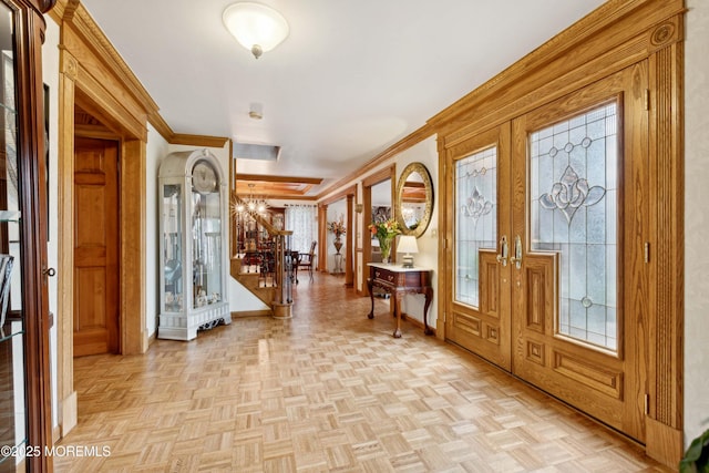 entryway featuring baseboards, ornamental molding, stairs, and a chandelier