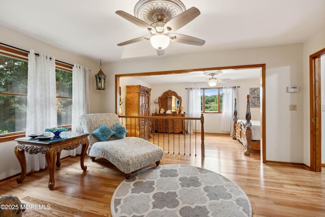sitting room featuring baseboards, a ceiling fan, and light wood-style flooring