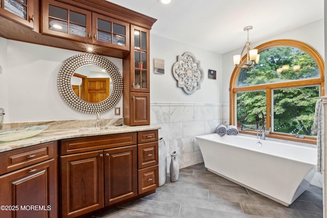 bathroom featuring an inviting chandelier, tile patterned flooring, a healthy amount of sunlight, and tile walls