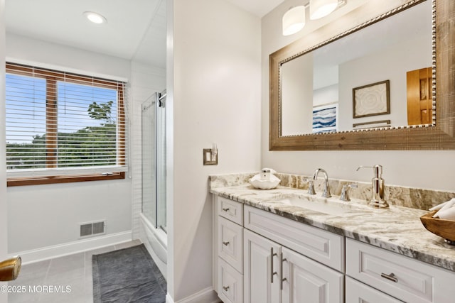 bathroom featuring tile patterned flooring, vanity, baseboards, combined bath / shower with glass door, and visible vents
