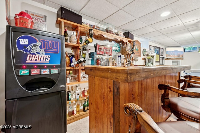 interior space with bar, carpet, and a drop ceiling