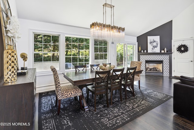 dining area with plenty of natural light, wood finished floors, high vaulted ceiling, and a tile fireplace