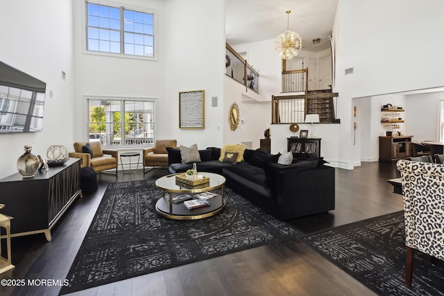 living area featuring a chandelier, visible vents, wood finished floors, and a towering ceiling