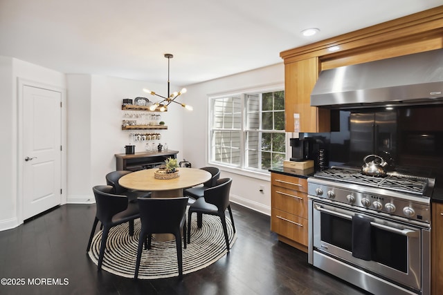 kitchen featuring wall chimney range hood, a chandelier, dark wood finished floors, range with two ovens, and baseboards