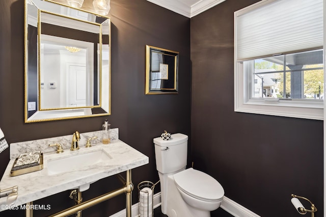 bathroom with crown molding, toilet, baseboards, and a sink