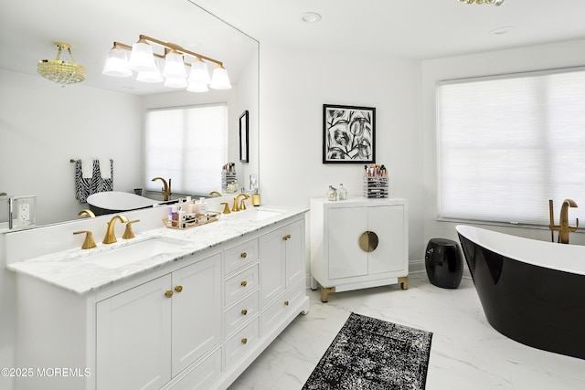 bathroom with a sink, a freestanding bath, double vanity, and marble finish floor
