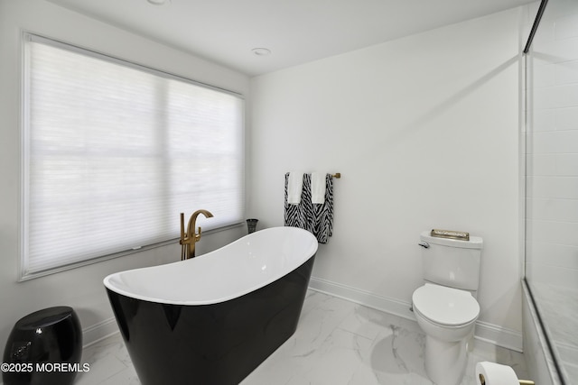 bathroom with toilet, baseboards, a freestanding bath, and marble finish floor