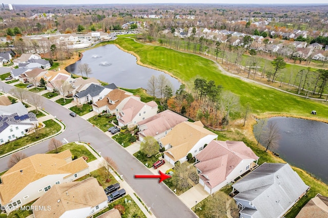 drone / aerial view featuring a water view, view of golf course, and a residential view