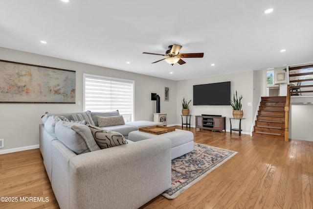living area with recessed lighting, light wood-style flooring, stairway, a wood stove, and a ceiling fan