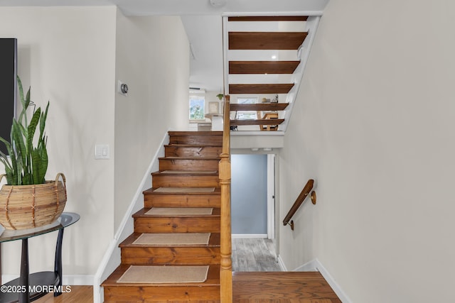 stairs featuring wood finished floors and baseboards