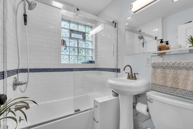 bathroom featuring combined bath / shower with glass door and toilet