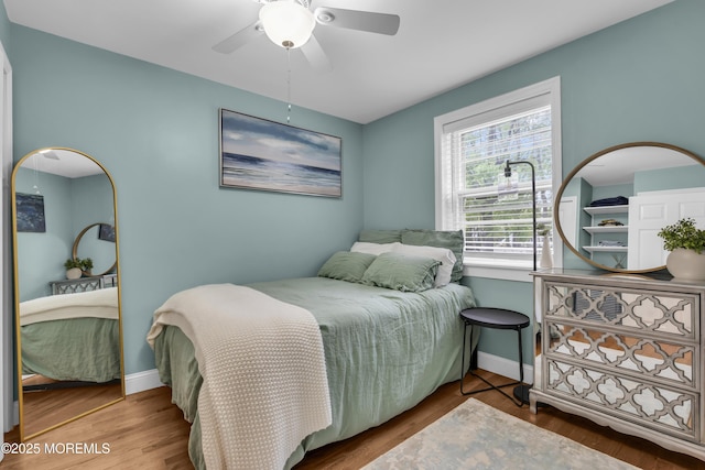 bedroom with a ceiling fan, wood finished floors, and baseboards