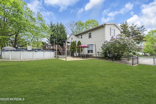 view of yard featuring a patio, a wooden deck, a fenced in pool, stairs, and fence