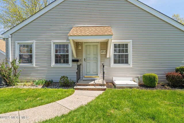 bungalow-style house featuring a shingled roof and a front lawn