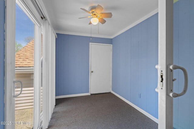 unfurnished bedroom featuring crown molding, baseboards, carpet, and a ceiling fan