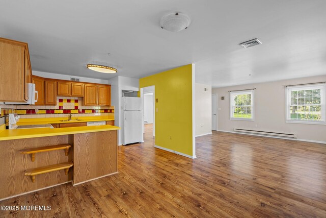 kitchen featuring a sink, white appliances, open floor plan, a baseboard radiator, and visible vents
