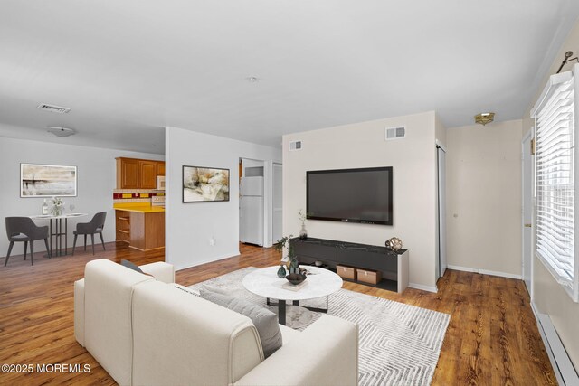 living room with baseboards, light wood-style flooring, and visible vents
