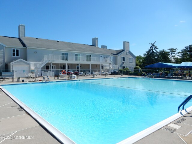 community pool with fence, stairs, and a patio area