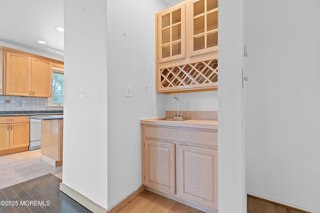 bar with indoor wet bar, baseboards, a sink, and light wood finished floors