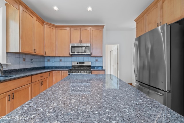 kitchen with recessed lighting, appliances with stainless steel finishes, tasteful backsplash, and dark stone countertops