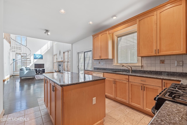 kitchen featuring black range with gas cooktop, tasteful backsplash, a sink, and a center island