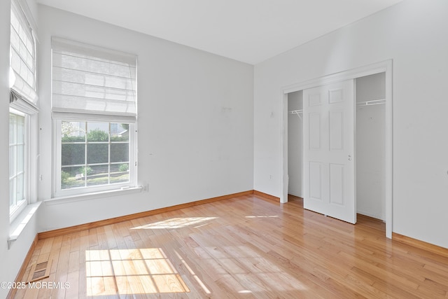 unfurnished bedroom with light wood-type flooring, baseboards, visible vents, and a closet