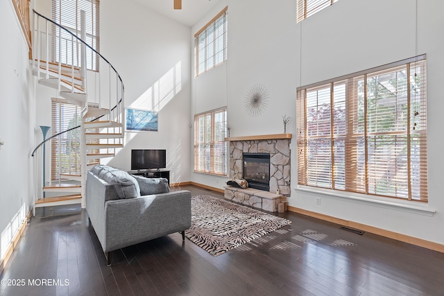 living room with visible vents, a fireplace, baseboards, a high ceiling, and stairs