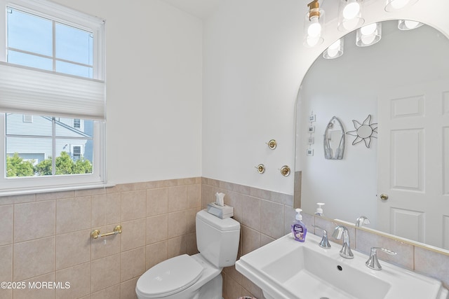bathroom featuring a sink, tile walls, toilet, and a wealth of natural light
