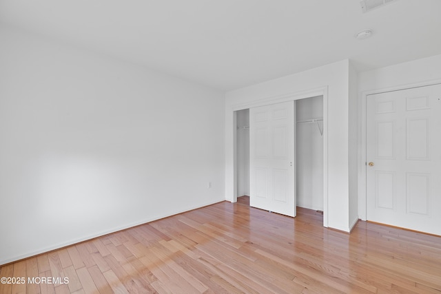 unfurnished bedroom with baseboards, light wood-style flooring, and a closet