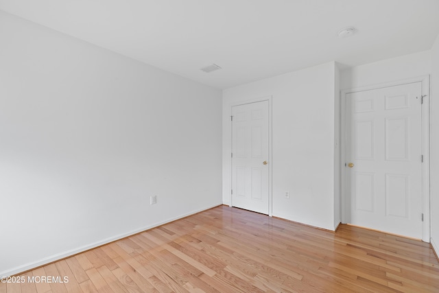 unfurnished bedroom with visible vents, light wood finished floors, and baseboards