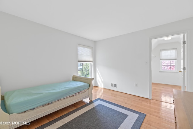 bedroom with baseboards, visible vents, multiple windows, and wood finished floors