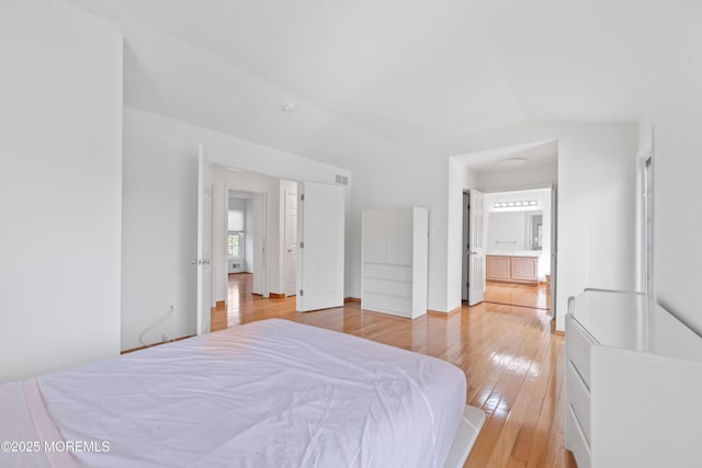 bedroom with light wood-style floors, connected bathroom, and visible vents