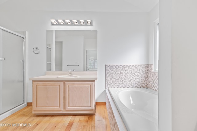 bathroom with a stall shower, wood finished floors, a bath, and vanity