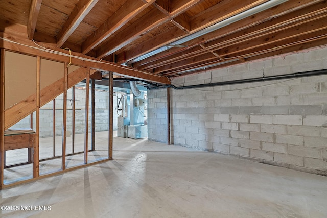 unfinished below grade area featuring heating unit and concrete block wall