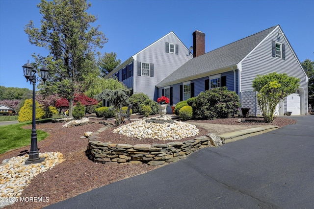 view of front of house featuring a chimney, a garage, and roof with shingles