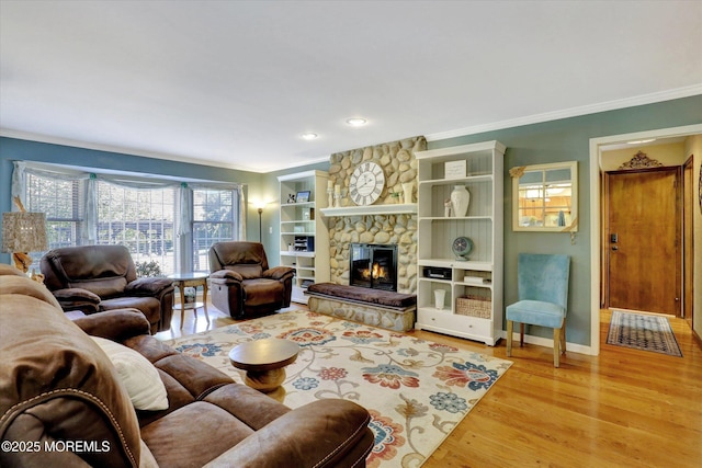 living area featuring ornamental molding, light wood-style floors, a fireplace, baseboards, and recessed lighting