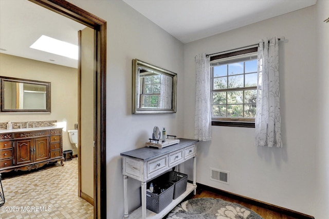 corridor with baseboards, a skylight, and a sink