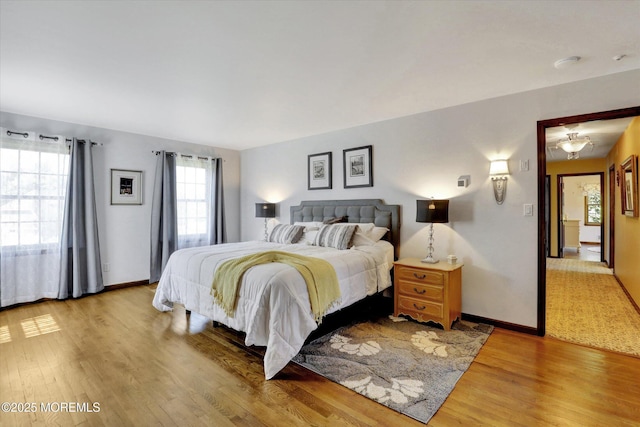 bedroom featuring light wood-style flooring, multiple windows, and baseboards