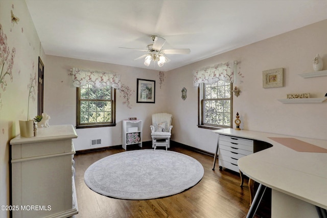 sitting room featuring ceiling fan, dark wood-type flooring, a desk, and baseboards