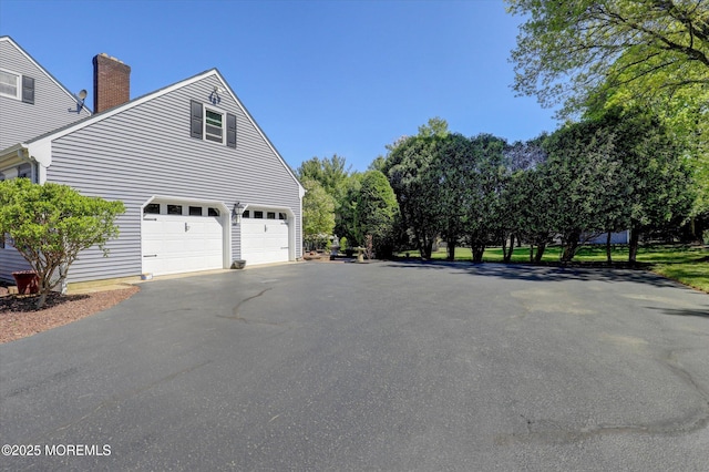 view of home's exterior with asphalt driveway and a chimney