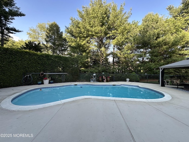 view of pool featuring a patio area, fence, a gazebo, and view of scattered trees